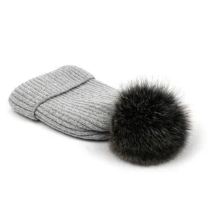 Detalle de un gorro de punto acanalado gris claro con un gran pompón de piel sintética