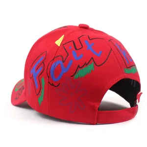 Dettaglio del cappellino rosso in cotone con graffiti Faith colorati e motivi floreali