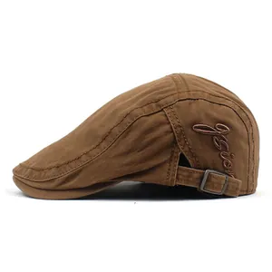 Détail du béret en coton marron montrant la broderie et la boucle métallique ajustable
