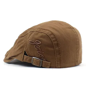 Détail du béret en coton marron montrant la broderie et la boucle de réglage en métal