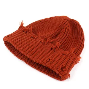 Close-up of caramel knit beanie with distressed fringe detail and ribbed texture