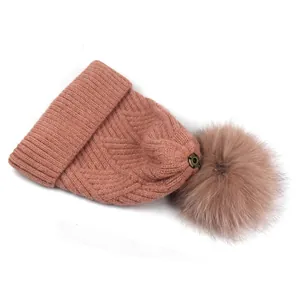 Makro-Detail des rosa Fischgräten-Strickmusters und Pelzbommels an der Wintermütze