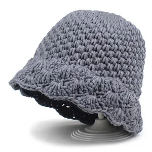 Close-up of grey knit bucket hat showing thick crochet texture and wavy brim design