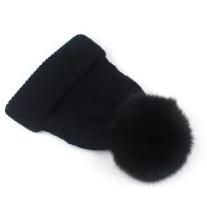Detailansicht der schwarzen Zopfstrickmütze mit flauschigem Kunstpelz-Bommel oben