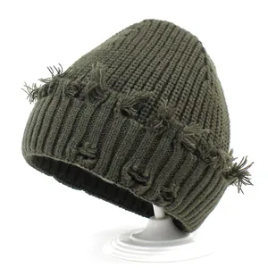 Distressed dark green ribbed knit beanie with frayed holes for a street style winter look