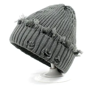 Close-up of grey knit beanie featuring distressed ripped details and ribbed texture