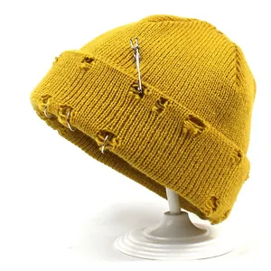 Mustard yellow ribbed knit beanie with silver rings and safety pin distressed design