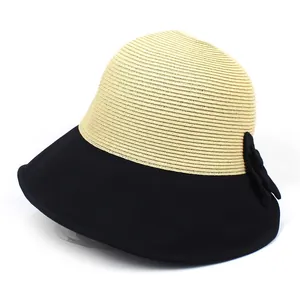 Détail du chapeau de paille d'été montrant la texture bicolore et le nœud noir élégant
