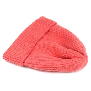Detailed macro view of the ribbed knit texture on a warm coral pink winter beanie hat