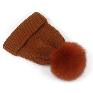 Detail von grobem Rautenstrickmuster und flauschigem Pelzbommel an der Wintermütze