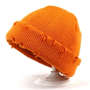 Berretto in maglia arancione brillante con trama a coste e dettagli usurati su supporto
