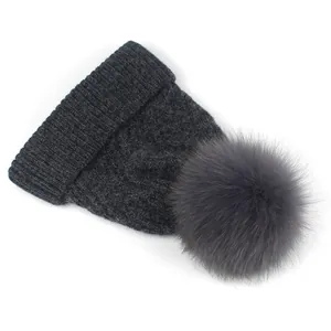Detail einer dunkelgrauen Strickmütze mit flauschigem Kunstfellbommel für Damen