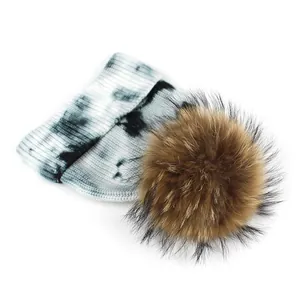 Women's tie-dye knit beanie with large fluffy faux fur pompom for winter warmth