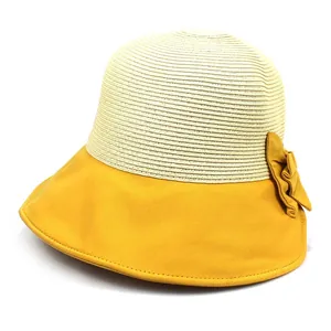 Détail d'un chapeau de paille à larges bords avec nœud en tissu jaune et surpiqûre