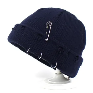 Navy blue knit beanie featuring silver rings, safety pin decor, and distressed hole details