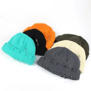 Detail of six colorful knit beanies with metal rings and safety pin punk accessories