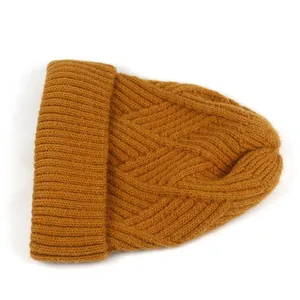 Detail der senfgelben Strickmütze mit Zopfmuster und geripptem Umschlag für den Winter