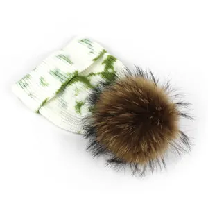 Detailed close-up of the plush faux fur pompom and tie-dye knit texture on the winter hat