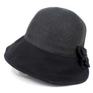 Détail d'un chapeau de soleil noir avec calotte tressée et décoration de fleur en tissu élégante