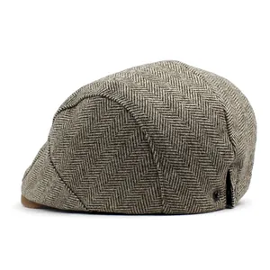 Close-up of herringbone pattern and metal button detail on a brown wool flat cap