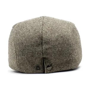 Detail of vintage herringbone pattern and metal button on brown wool flat cap