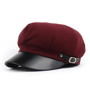 Detail of burgundy wool baker boy hat with black leather brim and metallic buckle
