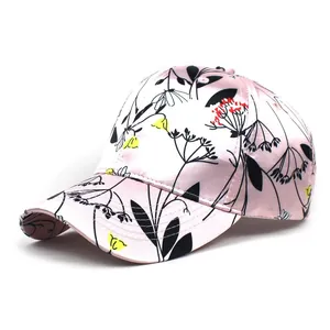 Detail view of pink satin baseball cap with colorful floral prints and curved brim