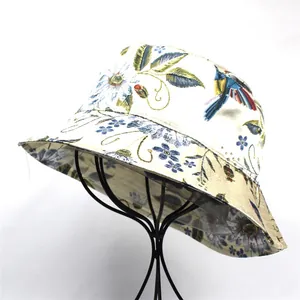 Close-up of floral and bird prints on a silk-like off-white foldable bucket hat