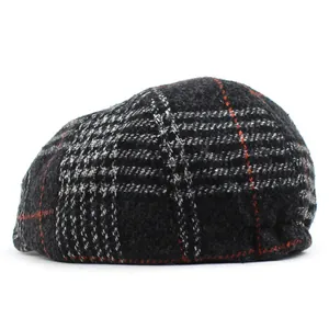 Detail of red and black checkered wool flat cap showing heavy texture and retro plaid pattern