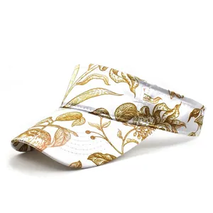 Detailed view of white sun visor hat with vintage gold palm leaf pattern and quality stitching
