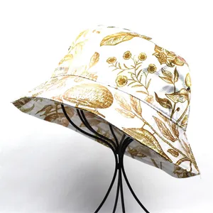 Close-up of white sun hat with vintage gold floral pattern and silk texture details