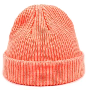 Detail of coral pink ribbed knit beanie showing cuffed edge and thick texture
