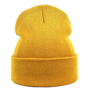 Close-up of the ginger yellow rib-knit texture and wide folded cuff of the acrylic beanie