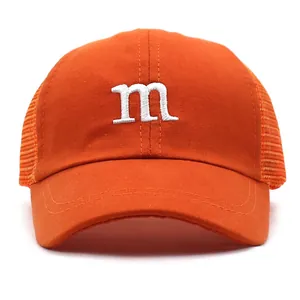 Close-up of bright orange trucker hat featuring white embroidered m logo and mesh back