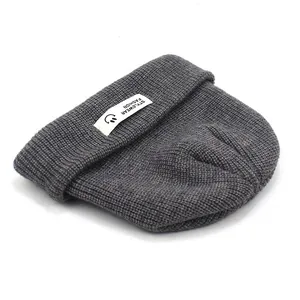 Detailstruktur der grauen Strickmütze mit weißem Stylewear-Mode-Patch und Rippenmuster