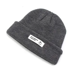 Detailaufnahme der dunkelgrauen Strickmütze mit Rippenmuster und modischem Webetikett