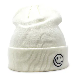 Dettaglio del berretto in maglia bianco panna con ricamo a faccina sorridente sul bordo