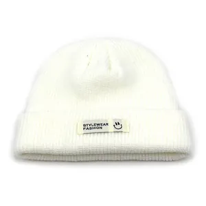 Detailansicht der weißen Acryl-Strickmütze mit aufgenähtem modischem Stoffaufnäher