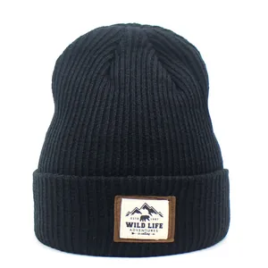 Detailed close-up of a black ribbed knit beanie featuring a mountain adventure fabric patch