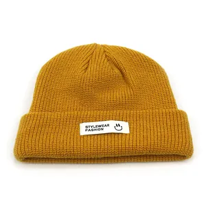 Detail der Strickstruktur einer senfgelben Beanie mit weißem Smiley-Logo-Etikett