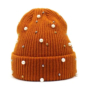 Detail der orangefarbenen Rippstrickmütze mit weißen Perlen und Metallperlen-Dekor