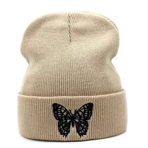 Detailopname van beige gebreide muts met een fijne zwarte vlinderborduring erop
