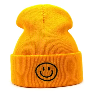 Dettaglio di un berretto in maglia gialla con logo smiley nero ricamato sul risvolto