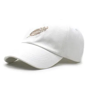 Vista detallada del bordado de pluma dorada en gorra de béisbol de algodón blanco
