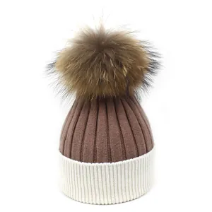 Détail du bonnet en maille bicolore avec rayures verticales et pompon en fourrure doux