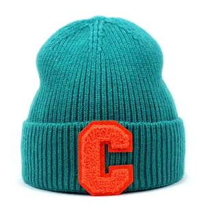 Detail of teal knit beanie with orange chenille letter C patch and ribbed texture