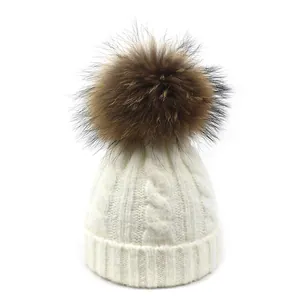Detalle de gorro de punto trenzado con pompón marrón y dobladillo acanalado grueso