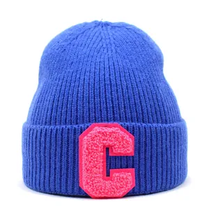 Close-up of royal blue knitted beanie featuring a pink textured letter C embroidery patch