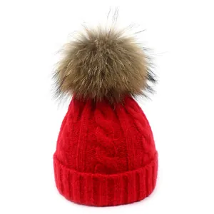 Detalle de un gorro de invierno rojo de punto de ochos con un pompón de pelo suave