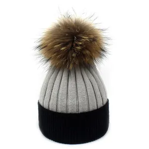 Détail de la maille côtelée avec pompon en fourrure marron sur bonnet gris et noir